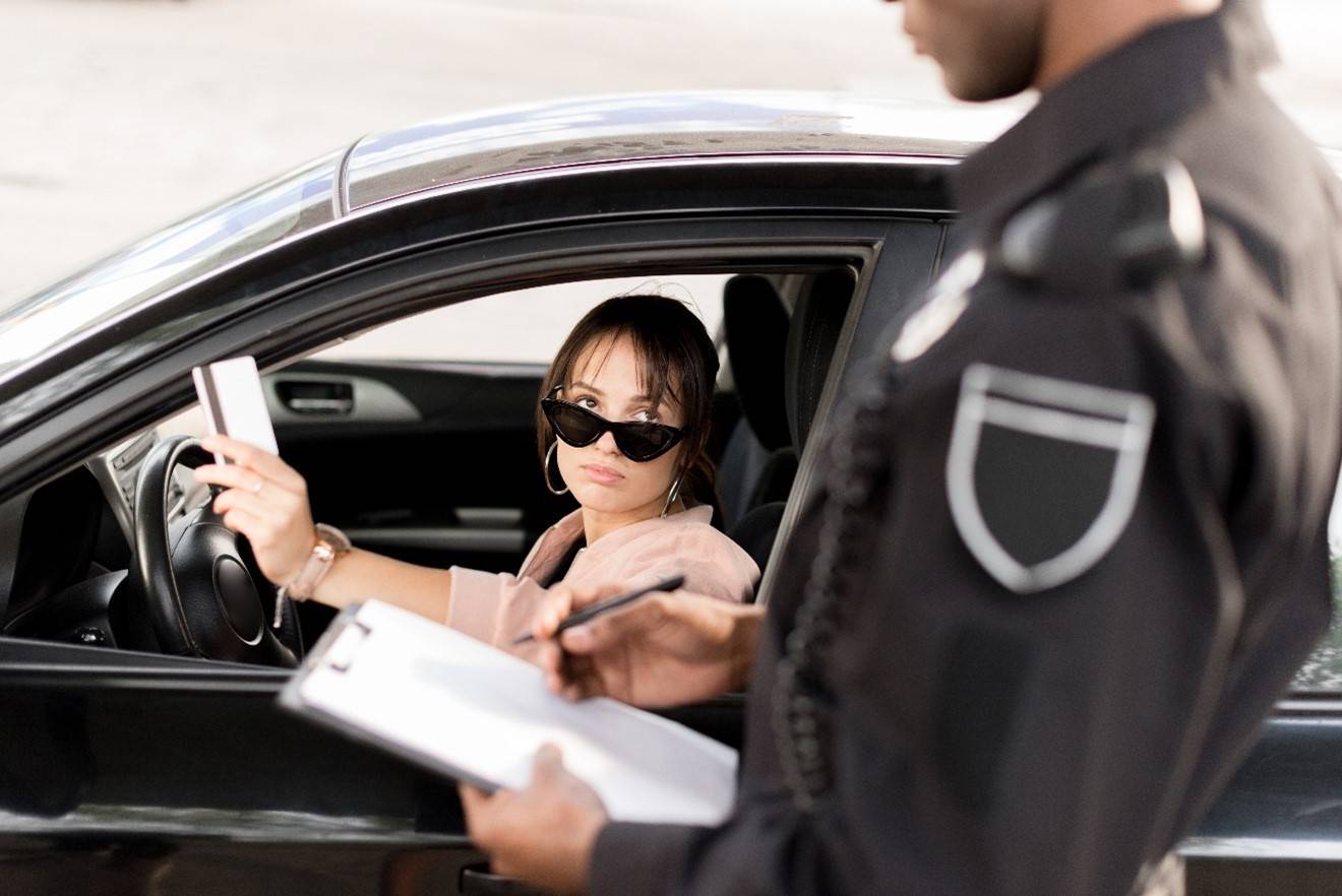 policeman holding clipboard talking to a woman in the car